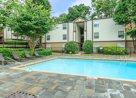A swimming pool in front of a building surrounded by trees.