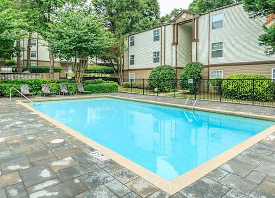 A small pool surrounded by a black fence and trees.