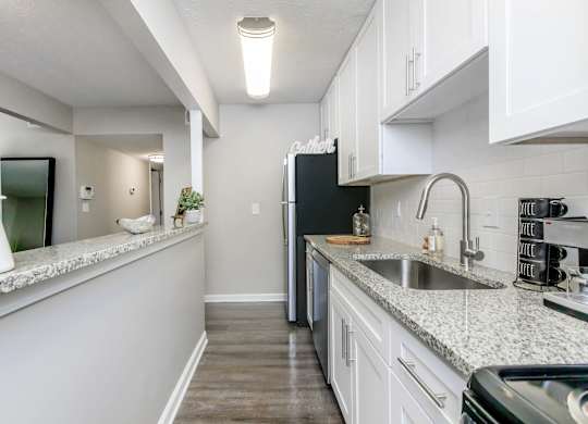 A kitchen with a black fridge and white cabinets.