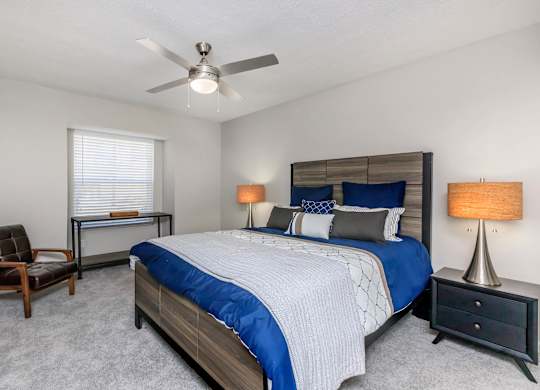 A bedroom with a bed, chair, and lamp.