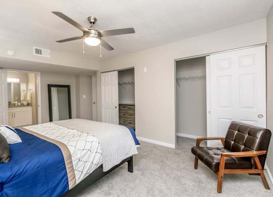 A bedroom with a blue bedspread and a brown leather chair.