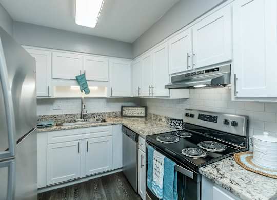 A kitchen with a stove top oven and a refrigerator at Crest at East Cobb Apartments, Georgia, 30062
