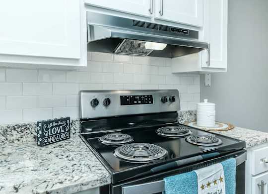 A black stove top with a pot on it and a sign that says at Crest at East Cobb Apartments, Marietta