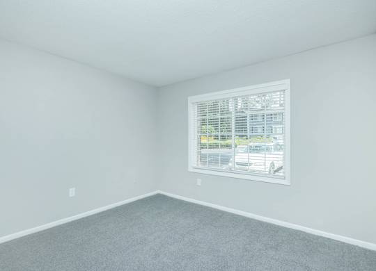 A room with a window and a grey carpet at Crest at East Cobb Apartments, Georgia