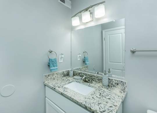 A bathroom with a marble countertop and a white sink at Crest at East Cobb Apartments, Georgia, 30062
