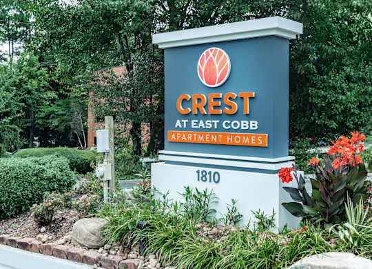 A sign for Crest at East Cobb Apartment Homes is shown in front of a landscaped area at Crest at East Cobb Apartments, Marietta, Georgia