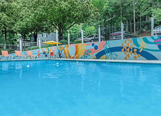 A pool with a blue water surface and a colorful mural on the side at Crest at East Cobb Apartments, Marietta, Georgia