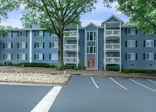 A large grey apartment building with a red door in front at Crest at East Cobb Apartments, Marietta, GA, 30062