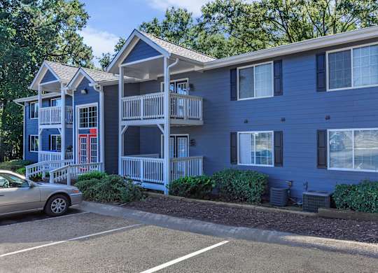 A blue two-story house with a car parked in front at Crest at East Cobb Apartments, Marietta, Georgia