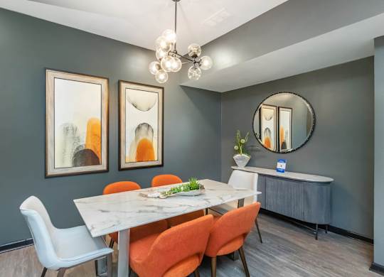 A dining room with a white table and orange chairs at Crest at East Cobb Apartments, Marietta, Georgia