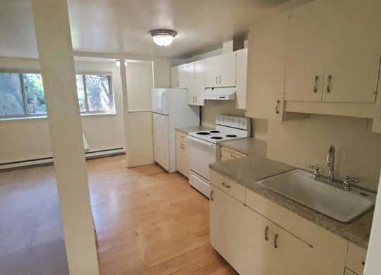 A kitchen with white cabinets and a wooden floor.