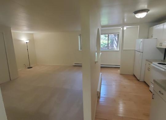 A kitchen with white appliances and wooden floors.