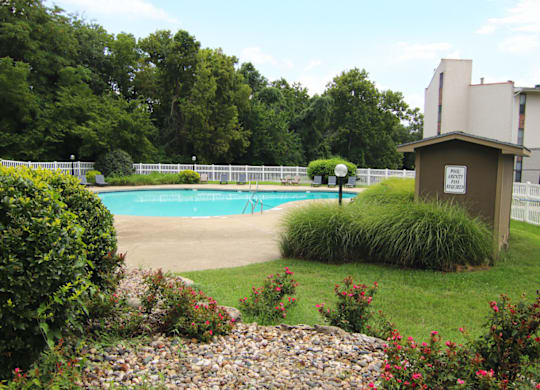 A pool surrounded by a fence and bushes. at Willow Creek, Kansas City, 64114