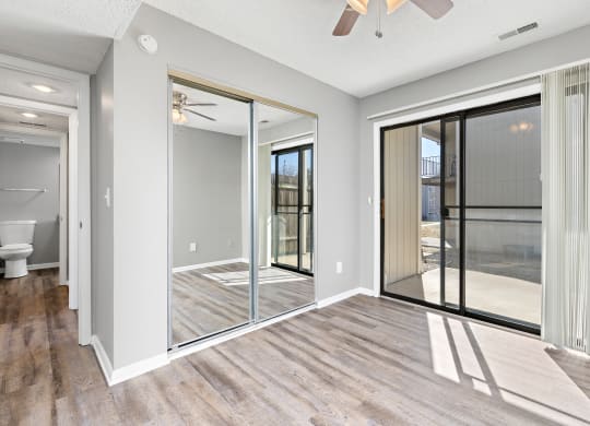 Living room with large patio door and closet with mirror doors at Eddingham in Lawrence, KS