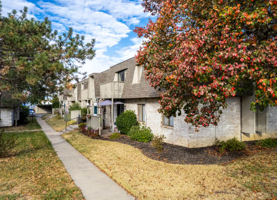 a sidewalk in front of a white brick apartment building
