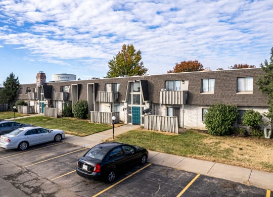 a parking lot with cars in front of an apartment building