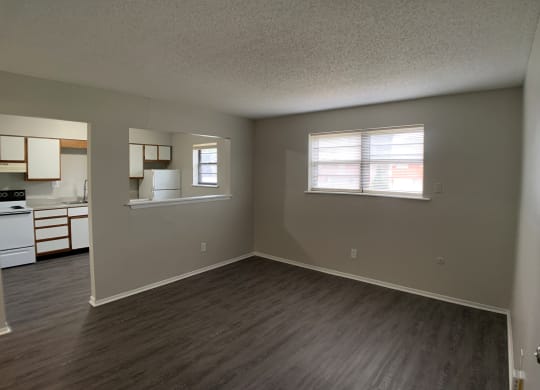 Spacious living room with vinyl flooring and open window into kitchen