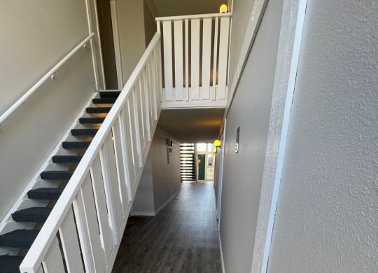 a look down the hallway of a house with hardwood floors and a staircase