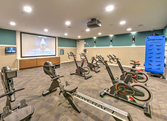 a gym with exercise bikes and a projection screen at Pinnacle Apartments, Jacksonville, FL
