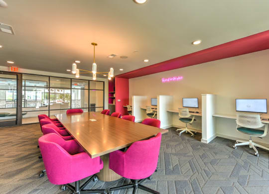 a conference room with a wooden table and pink chairs  at Pinnacle Apartments, Jacksonville, Florida