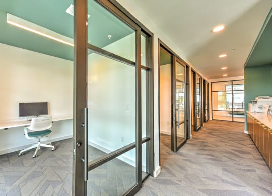 a corridor with a desk and a computer in a room with glass doors at Pinnacle Apartments, Jacksonville