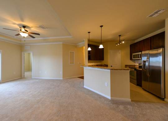 Kitchen and living room with white appliances and brown cabinets at Cabana Club - Galleria Club Apartments, Jacksonville, FL, 32256