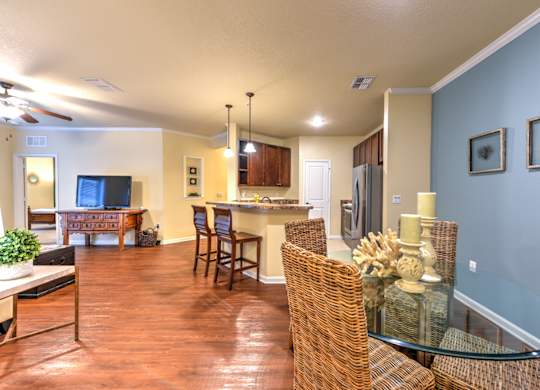 A living room with a glass table and wicker chairs at Cabana Club - Galleria Club Apartments, Florida