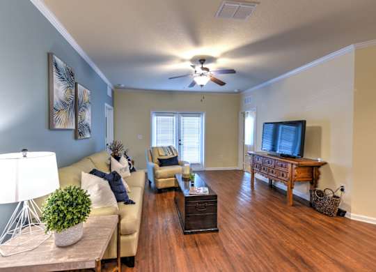 A living room with a couch, a coffee table, and a ceiling fan at Cabana Club - Galleria Club Apartments, Jacksonville, FL, 32256