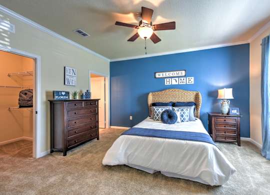 A bedroom with a bed, dresser, and ceiling fan at Cabana Club - Galleria Club Apartments, Jacksonville