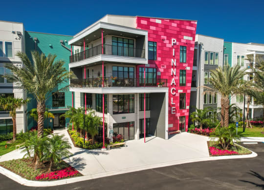 a building with a red and white facade and palm trees at Pinnacle Apartments, Jacksonville, FL, 32256