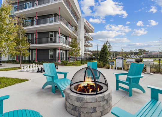 a fire pit with blue chairs in front of an apartment building at Pinnacle Apartments, Jacksonville, 32256