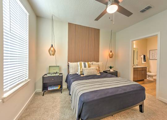 A bedroom with a bed, nightstand, and a ceiling fan at Fusion Apartments, Florida