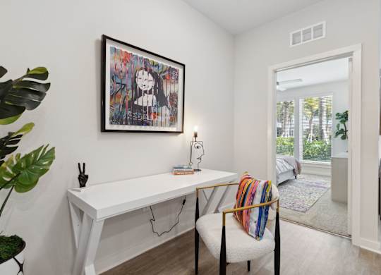 A room with a white desk and a chair with a colorful throw pillow. at Pinnacle Apartments, Jacksonville, 32256