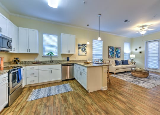a kitchen and living room with hardwood floors and white cabinets at Palm Bay Club, Jacksonville, 32258