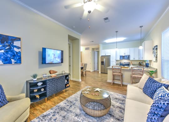 a living room and kitchen with a flat screen tv and a coffee table