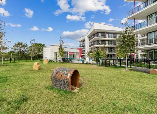 A playground with a wooden tunnel in the middle of a grassy area with apartment buildings in the backgroundat Pinnacle Apartments, Jacksonville, FL