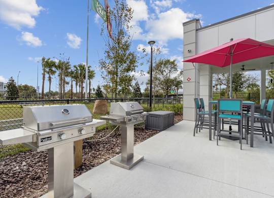 A barbecue grill is in front of a building with a red awningat Pinnacle Apartments, Jacksonville, FL