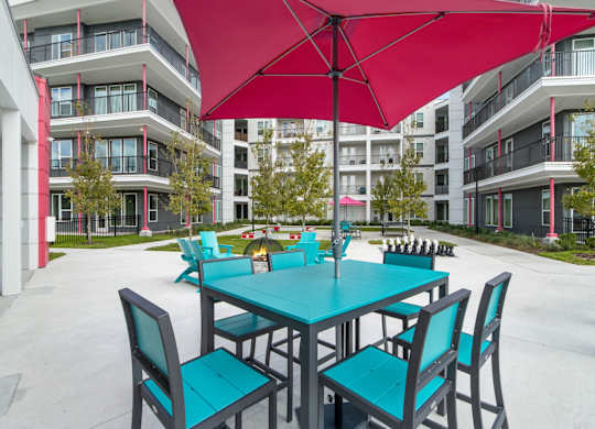 A red umbrella shades a table and chairs in a courtyardat Pinnacle Apartments, Jacksonville, FL