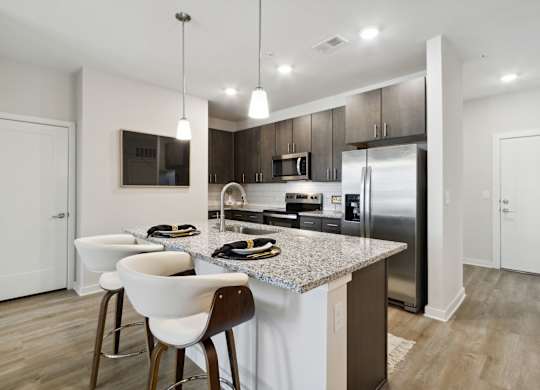 A modern kitchen with a granite countertop and stainless steel appliancesat Pinnacle Apartments, Jacksonville, FL