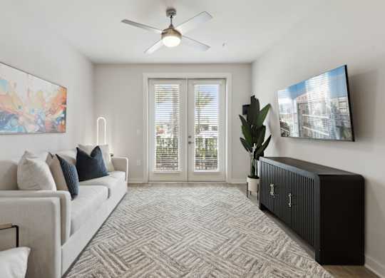A living room with a couch, a fan, and a painting on the wallat Pinnacle Apartments, Jacksonville, FL
