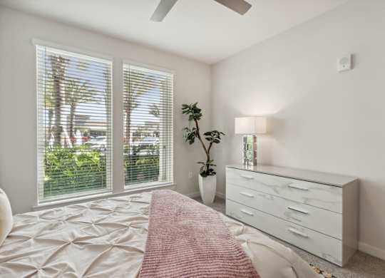 A bedroom with a bed, dresser, and window with blindsat Pinnacle Apartments, Jacksonville, FL