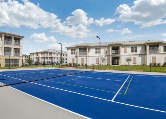 a blue tennis court with apartments in the background  at Palm Bay Club, Jacksonville, 32258