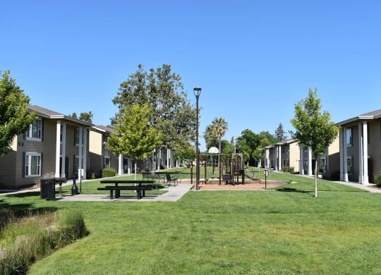 Mutual Housing on the Greenway playground and picnic tables as seen across the lawn