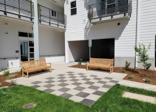 Large checker board concrete area with park benches in courtyard.