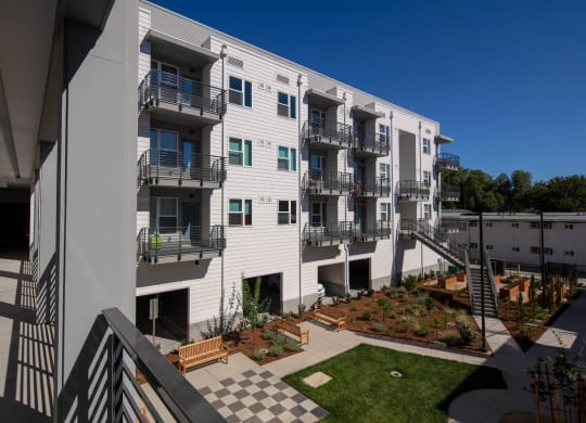 Interior courtyard from balcony, looking down on green space, exterior staircase, and garden.