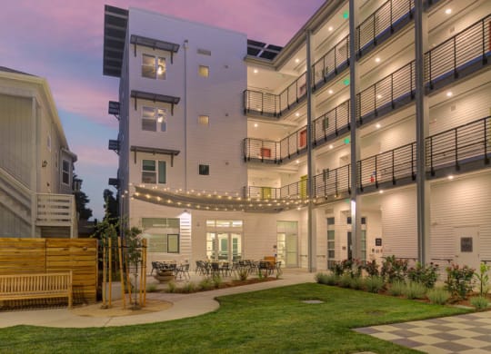 Interior courtyard at dusk with string lights and walkway lights illuminating courtyard.