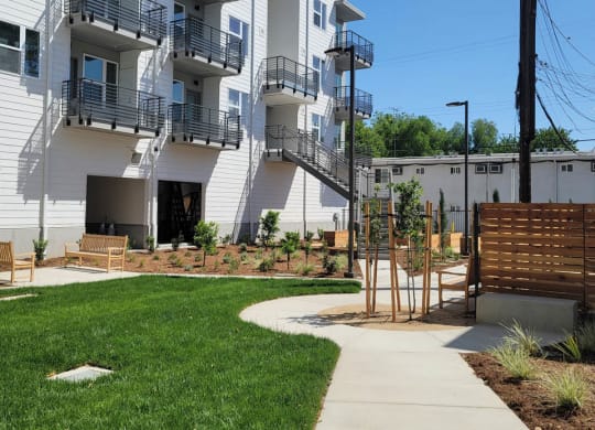 Courtyard at Lavender with large green space, walkways, and 4 story white building.