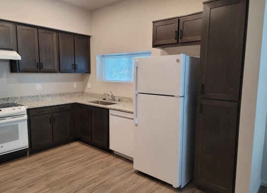 Kitchen with dark wood cabinets and white appliances.
