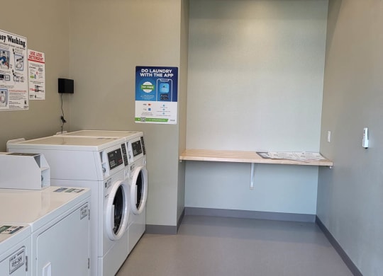 Laundry room at Lavender with two washing machines and dryers and a folding table.