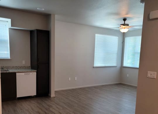 Living room and partial kitchen at Lavender with wood floors, dark cabinets, and white dishwasher. room at overhead lights and windows.
